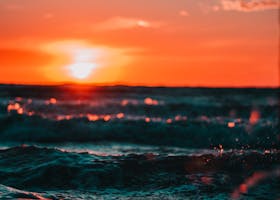 Stunning sunset over ocean waves with vivid colors and sun flare, creating a serene seascape.